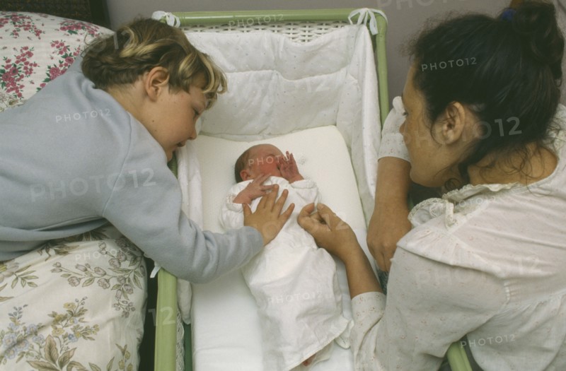 CHILDREN, Relationships, Siblings, Mother and five year old son looking at week old sister lying in cot.