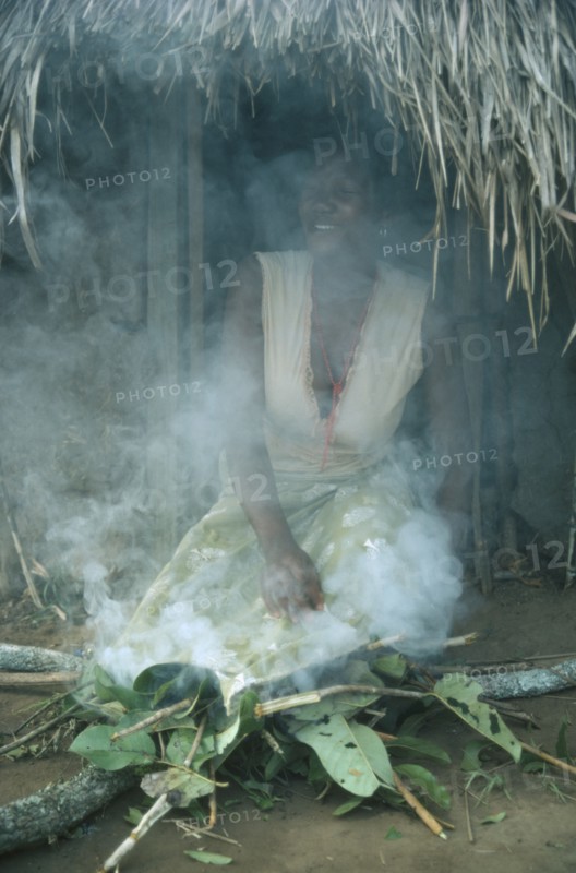 SUDAN, South, Rituals, Azande tribeswoman kneeling over fire to purify herself after giving birth.