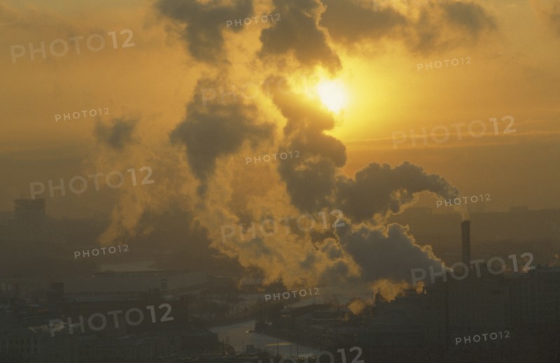 RUSSIA, Moscow, Setting sun partly obscured by plume of thick smoke from industrial chimney.