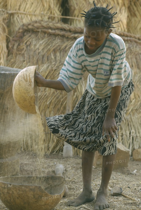 BURKINA  FASO, Bisaland, Sigue Voisin, Near Garango. Young girl winnowing.