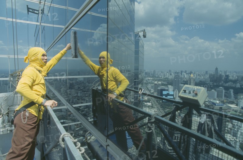 THAILAND, Bangkok, "Man on a lift, cleaning the outside windows of a large building."