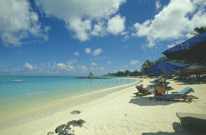 MAURITIUS, Grand Bay, The beach at the Mauritius Hotel. People on sun loungers  and umbrellas.