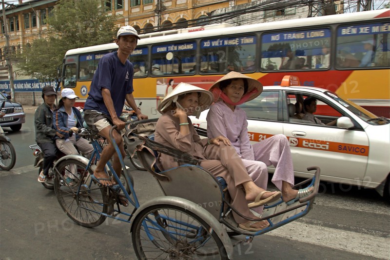 VIETNAM, South, Ho Chi Minh City, Passengers riding in a cyclo in heavy traffic down a busy street