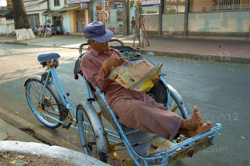VIETNAM, South, Ho Chi Minh City, A Cyclo driver reading a magazine taking a break