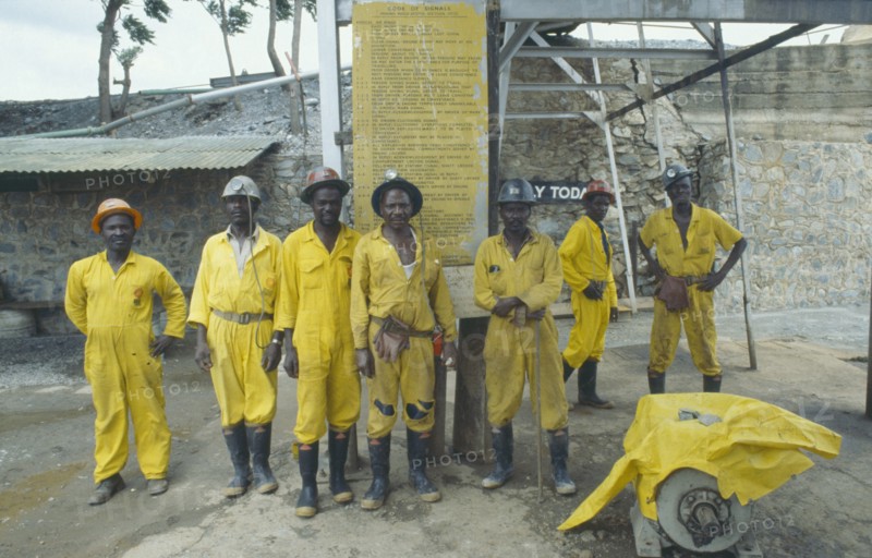 ZIMBABWE, Industry, Group of miners in safety helmets and work clothes at Patchway gold mine with Code of Signals mining regulations notice behind them.