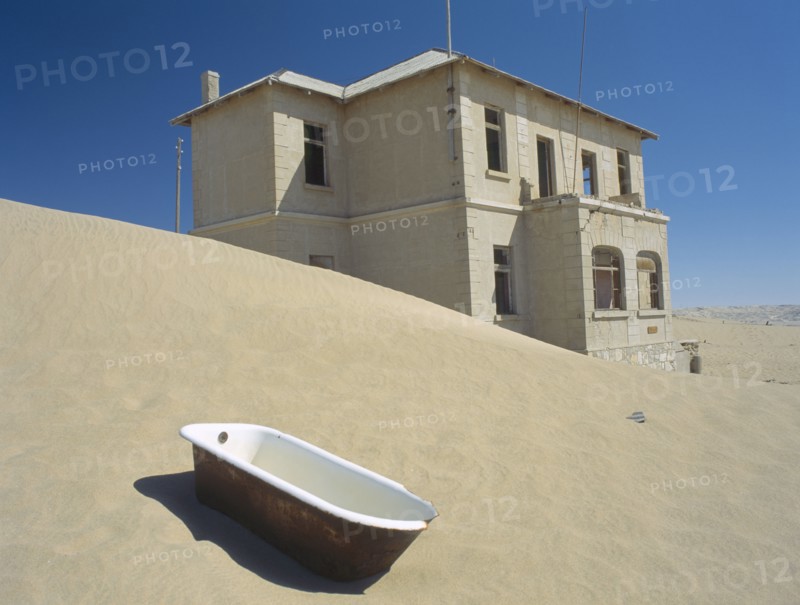 NAMIBIA, Kolmanskop, A house with a bath tub in the foreground  with desert sands encroaching.