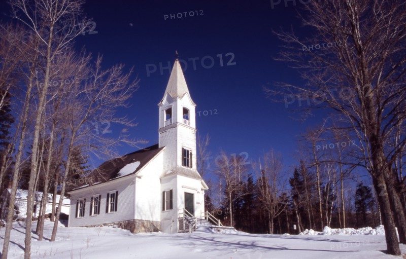 USA, New Hampshire, Jefferson, "Saint Johns United Methodist Church, small white building with spire and steps leading to entrance, surrounded by snow with some on roof."