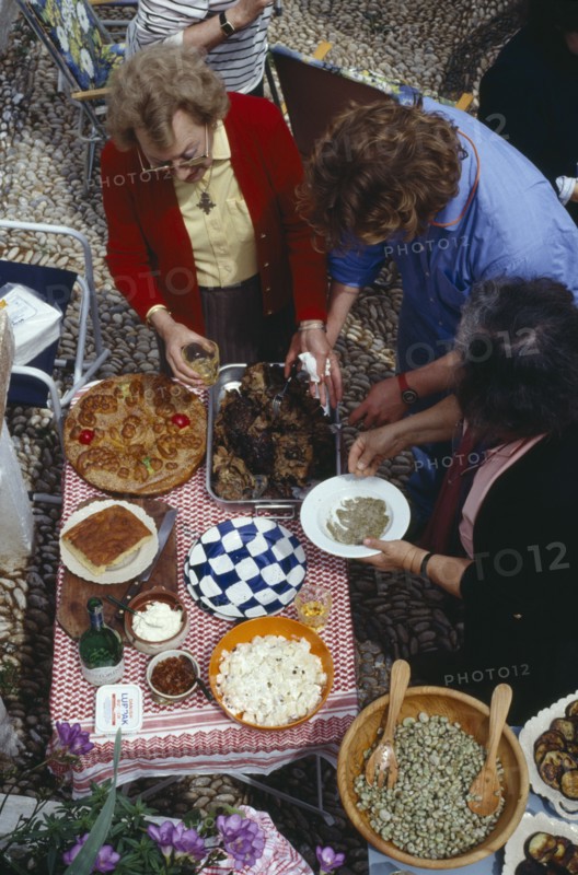 GREECE, Saronic Islands, Spetses, Women serving traditional meal for Feast of the Spitted Lamb held on Easter Day.