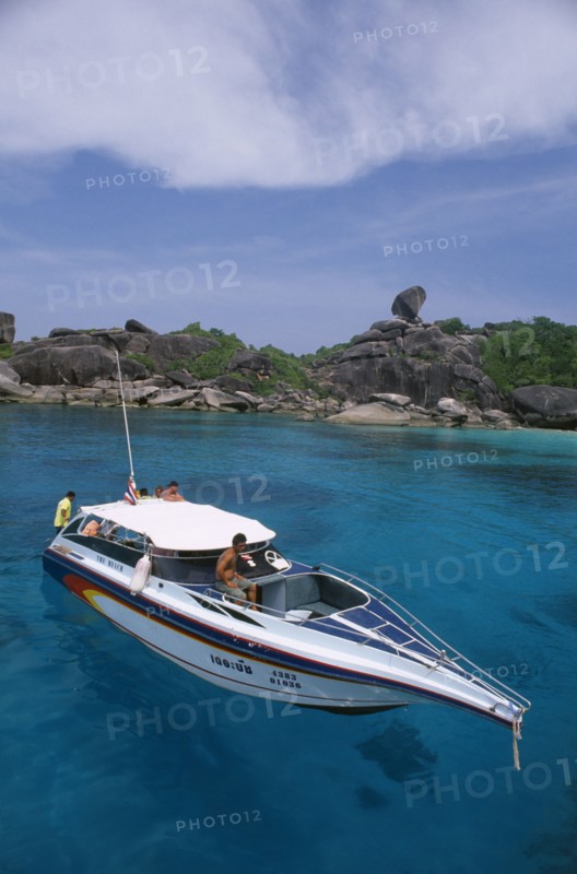 THAILAND, Similan Islands, Ko Bangu, People on board a small motor boat near the rocky shore.