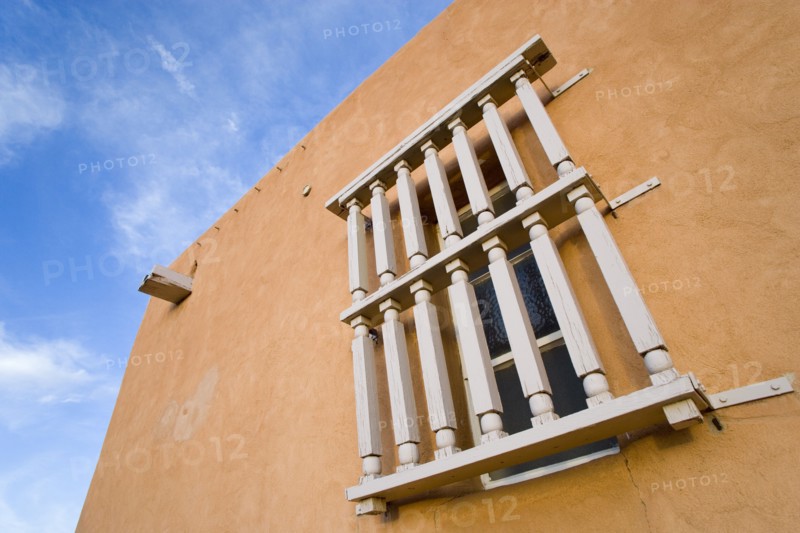 USA, New Mexico, Santa Fe, Wooden barred window on the side of an adobe style Pueblo Revival building