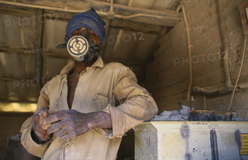 MALAWI, Dedza, Dedza Potteries producing Fair Trade goods for export.  Craftsman wearing protective mask and overalls to grind rock.