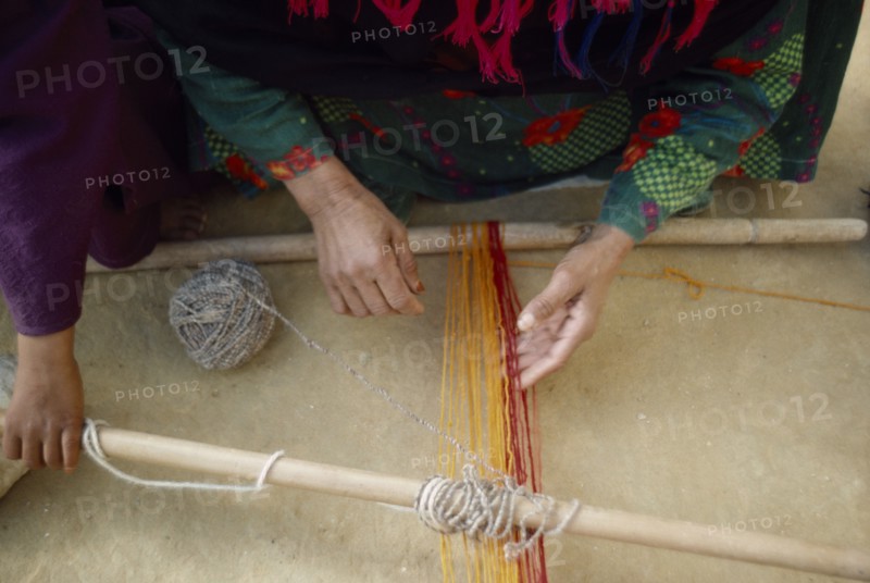 EGYPT, Western Desert, Bedouin, Cropped view of Bedouin woman and child weaving coloured yarn.