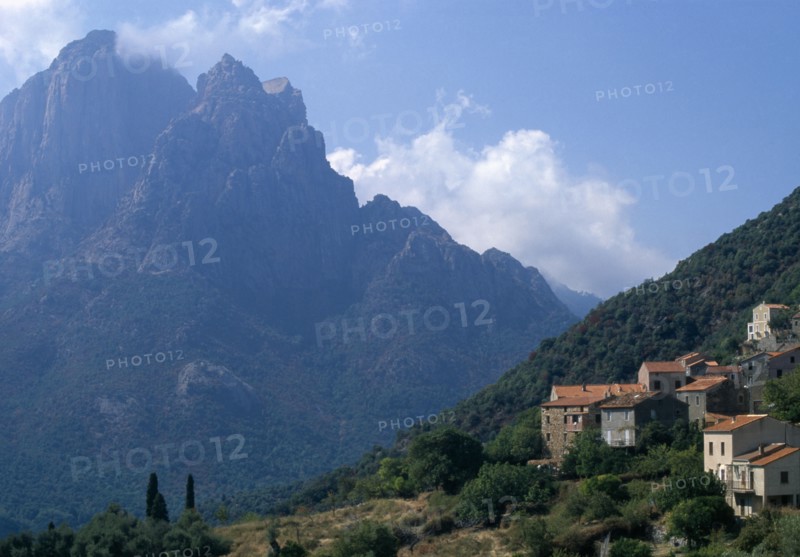 FRANCE, Corsica, The cusp shaped summit of Capo D’Orto provides a dramatic backdrop to the hillside village of Ota
