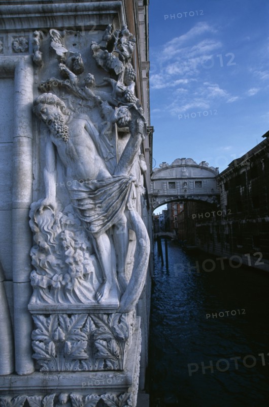 ITALY, Veneto, Venice, The Doges Palace. Relief carving of The Drunkenness of Noah or The Vine Angle on the corner of building beside The Bridge of Sighs with water below