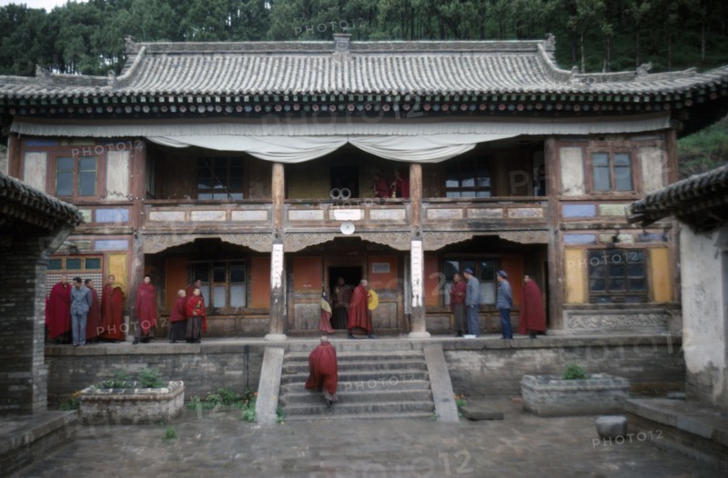 CHINA, Qinghai Province, Quezhang Lamasery, Tibetan Yellow Hat Buddhist monks on balcony and veranda of monastery.