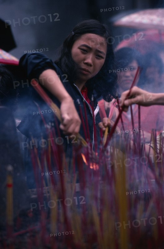 CHINA, Guangzhou, People, Young woman lighting incense at temple.