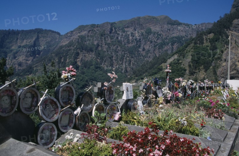 PORTUGAL, Madeira, Camara de Lobos, Curral das Freiras. Photographs of the dead with flowers outside the Church of Senhora do Livramento which are removed after five years