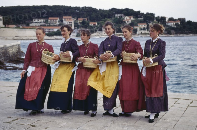 CROATIA, Dalmatia, Hvar Island, Girls in traditional clothing holding baskets greeting arriving visitors