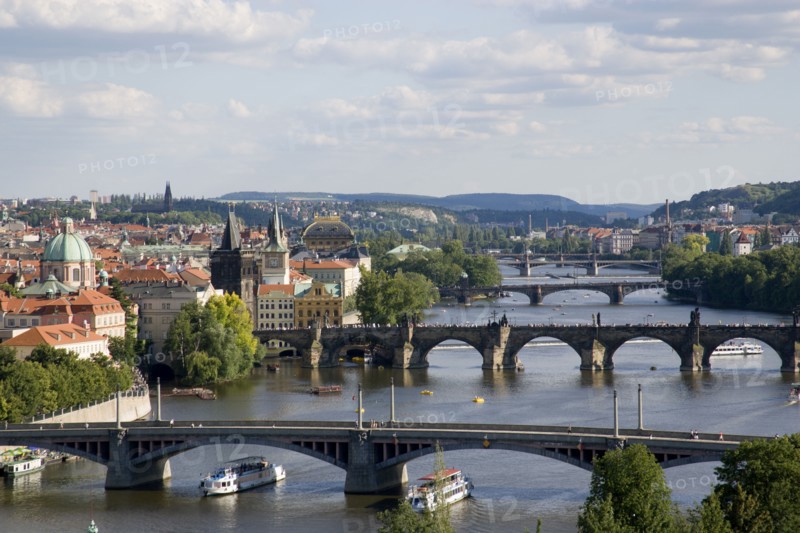 CZECH REPUBLIC, Bohemia, Prague, The city skyline with the bridges across the Vtlava River and cruise ships passing beneath them
