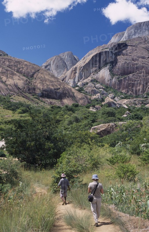 MADAGASCAR, Ambalavao, A tourist being lead by a guide towards rocky mountains and trees in the Anjaha Nature Reserve