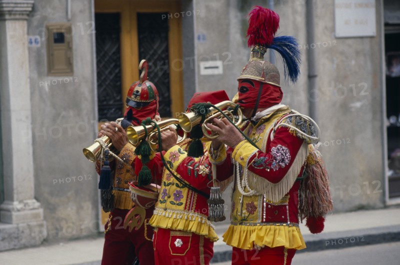 ITALY, Sicily, San Fratello, Bugle players wearing red and yellow costumes and masks celebrating the Feast of the Jews just before Easter.