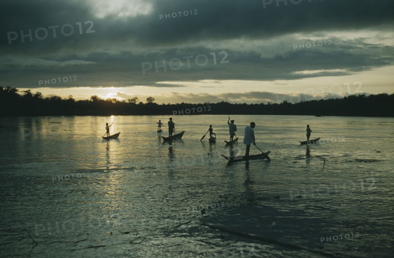 COLOMBIA, Choco Region, Noanama Tribe, Boys paddling canoes on lower rio San Juan at dusk
