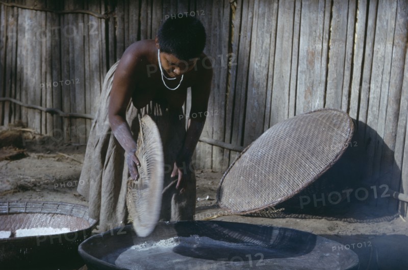 COLOMBIA, Vaupes Region, Tukano Tribe, Girl prepares clay oven for baking “casabe” yucca flour into Tukano daily bread