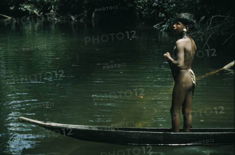 COLOMBIA, Choco Region, Noanama Tribe, "Ricardino, a young boy with a silver ear plug paddles his canoe upstream towards the family cultivation plot "