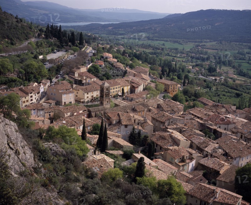 FRANCE, Provence Cote d’Azur, Alpes Haute de Provence, View South over the roof tops of the village Moustiers Saint Marie with the Saint Croix lake in the background