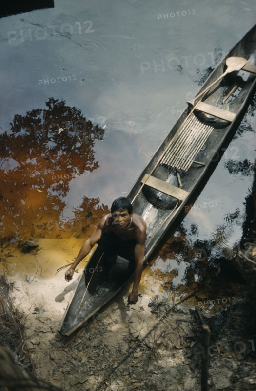 COLOMBIA, Vaupes Region, Tukano Tribe, Man beaches his canoe at a river port; note fishing rod and typically shaped Amazonian paddle.