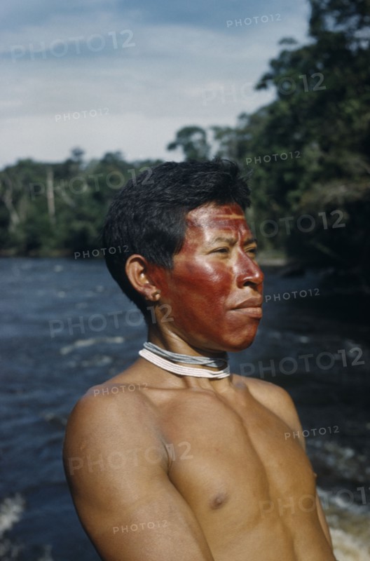 COLOMBIA, Vaupes Region, Tukano Tribe, "Portrait of Marco, a hunter with red “karajuru” facial paint, wooden ear-plug and strings of precious white and pale blue glass beads (traded throughout Amazonia)"