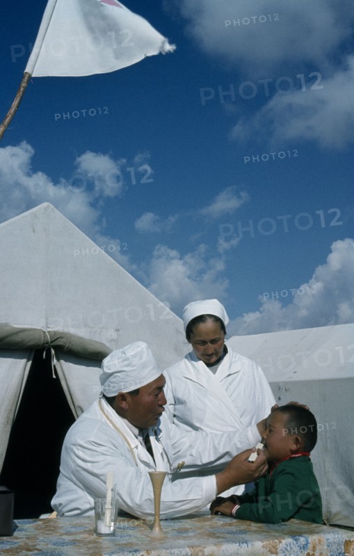 KAZAKHSTAN, Kirgiziya, Mountain doctor and nurse treating young boy.