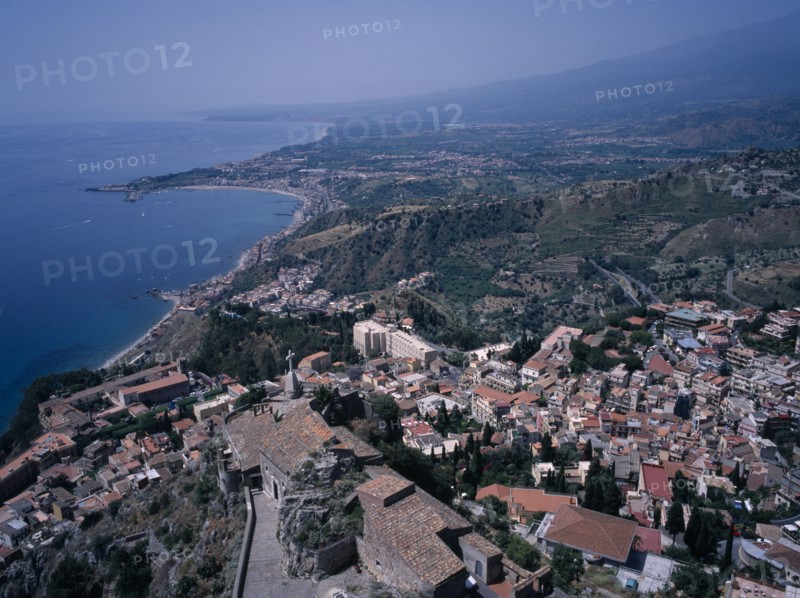 ITALY, Sicily, Messina, View South over the rooftops of  the town of Taormina to Giardini Naxos.