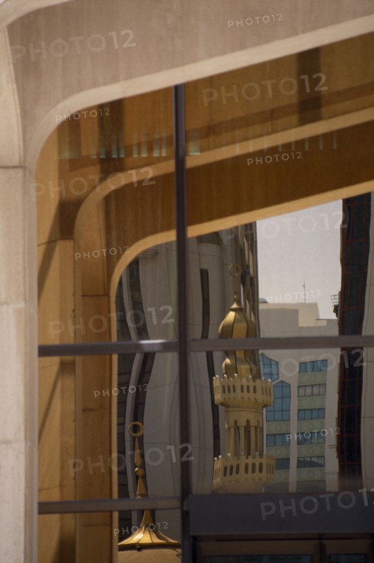 UAE, Abu Dhabi, Arabian Monetary Fund Head Office building. Detail of  windows with minarets and tall buildings reflected in the glass