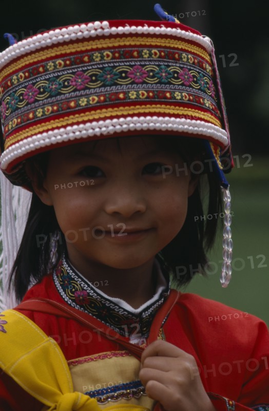 CHINA, Yunnan, "Near Kunming. Portrait of a young Sani girl at the Stone Forest, wearing a decorated hat with bead trim."