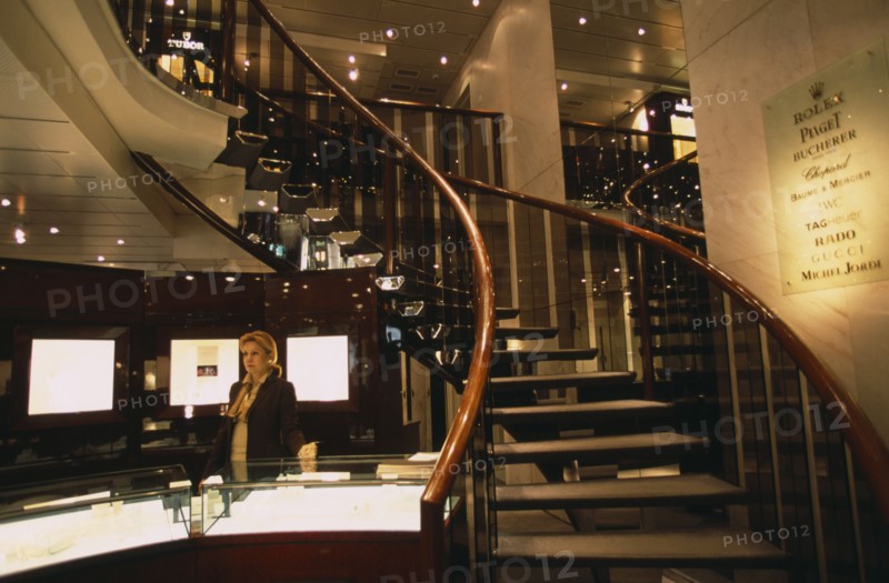 SWITZERLAND, Geneva, Interior of jewellery shop on Rue du Rhone with sales assistant standing behind display counter.