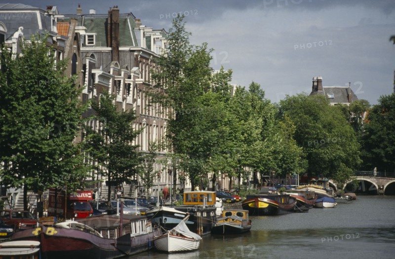 HOLLAND, Amsterdam, Canal and moored houseboats and barges overlooked by traditional architecture.