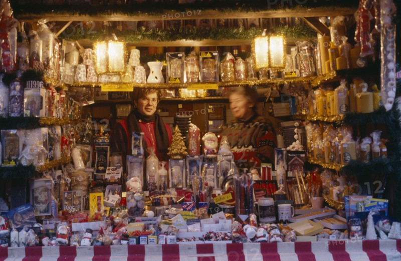 GERMANY, Bayern, Nuremberg, "Women vendors in decorated stall in Christmas market selling glassware, candles and Christmas decorations."