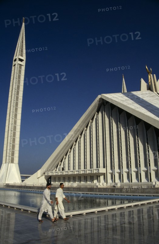 PAKISTAN, Islamabad, "Worshippers walking past the pool at the Shah Faisal mosque.  Part view of roof and minaret behind.  Design by Vedat Dalokay, construction completed 1986."