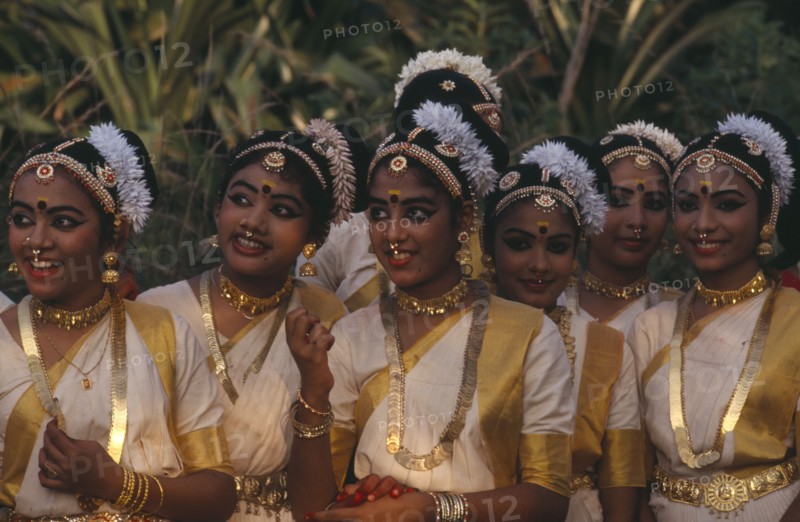 INDIA, Kerala, Thiruvananthapuram, "Mohiniyattam dancers at The Great Elephant March festival. A group of young girls with hair decoration, gold jewellery, earrings and nose rings."