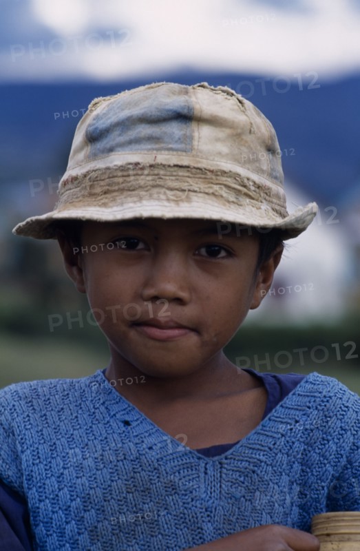 MADAGASCAR, People, children, Road to Ambositra. Portrait of a young boy wearing a dirty hat and blue knitted sweater