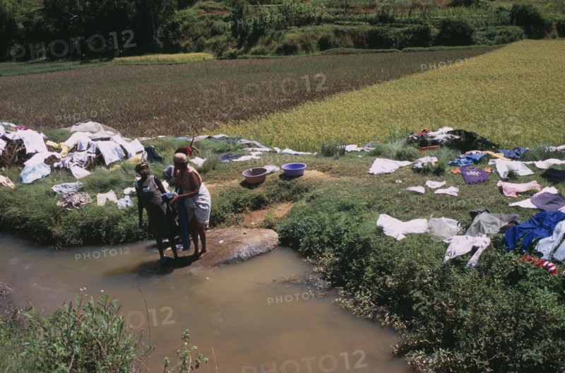 MADAGASCAR, Work, Near Ambositra. Women doing laundry in a river with the clothes left to dry in the sun along the river banks