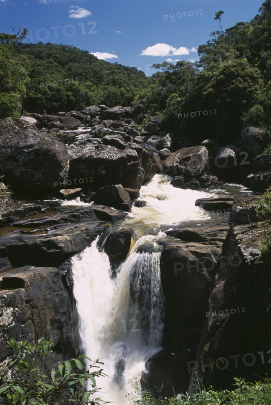 MADAGASCAR, Ranomanfana National Park, Waterfalls cascading over rocks surrounded by lush green tropical rainforest