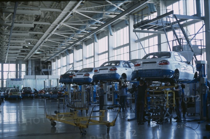 UKRAINE, Zaporozhye, Cars raised off the ground with staff working underneath in a production factory.