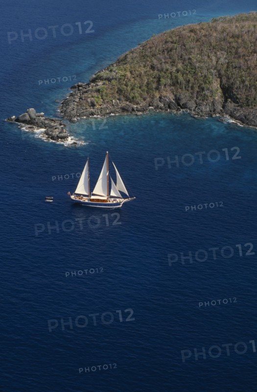 WEST INDIES, US Virgin Islands, St Thomas, Elevated view over sailing boat passing rocky projectory.