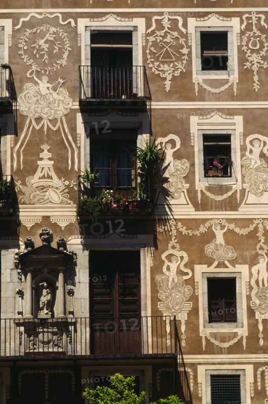SPAIN, Catalonia, Barcelona, Decorated exterior of flats on the Plaza Delfi with potted plants and flowers on the balconies and window sills.