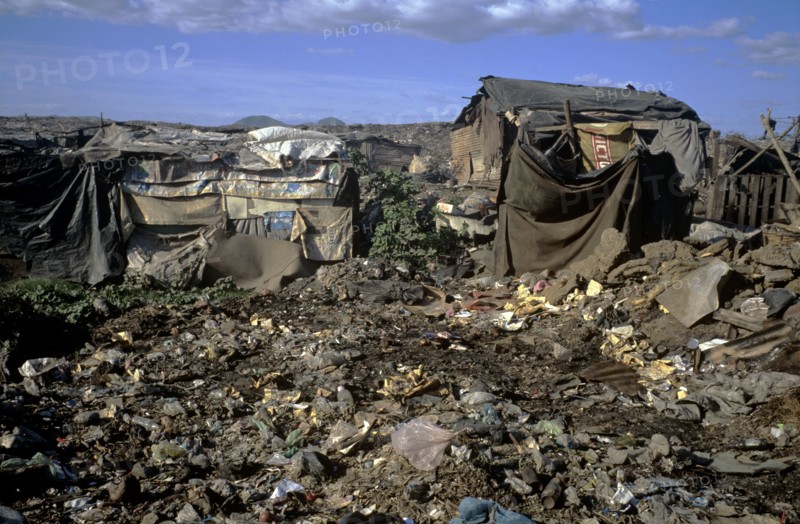 NICARAGUA, Managua Province, Managua, "The 'waste basket of Chureca' has existed since the late 1960's in the Acahualinca district of Managua, Nicaragua. It covers 42 hectares, is bombarded with thousands of tonnes of waste a day and is home to over 170 struggling families. By day over 1500 more Nicaraguans arrive at the site, some of whom are children who have been sent by their parents, others come by their own initiative. All compete with the adults to find, harvest and re-sell recyclable material. Of the minors who go to the waste basket - 88% it has respiratory problems, 62% suffer from parasites and 42% have serious skin diseases. Although the sky is clear and blue the air is thick of burning waste or rotting waste. Little houses or 'casitas' lie in a mixed muddle of rubbish and waste. The houses at the back of shot are made up of an eclectic collection of doors, wooden planks, dustbin bags, hanging bits of ripped tarpaulin, corrugated iron strips and whatever waste material seem...