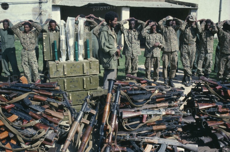 ERITREA, Military, Eritrean People’s Liberation Front soldier with prisoners and captured arms.