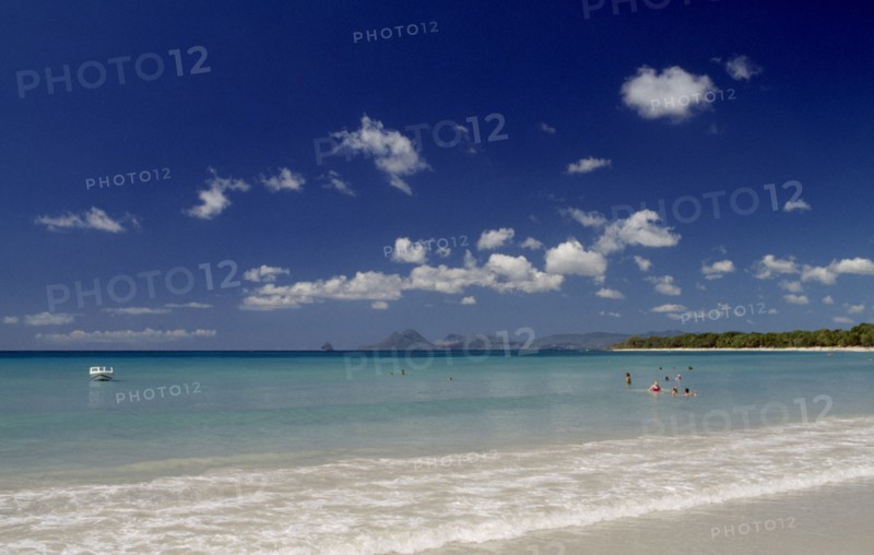 MARTINIQUE, Landscape, Beach, View from the waters edge across calm clear turquoise sea with people swimming in the water and hills seen in the distance