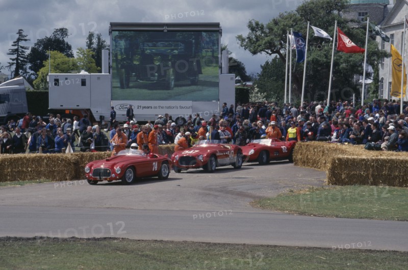 ENGLAND, West Sussex, Goodwood, Festival of Speed. Three red Ferraris 2 litre built in 1950 4.1 litre 1953 and 4.1litre 1957. Crowds of spectators gathered around circuit